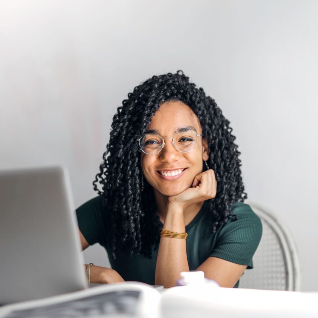 African american woman smiling while working at her computer, listening to her frustration as a call to shift